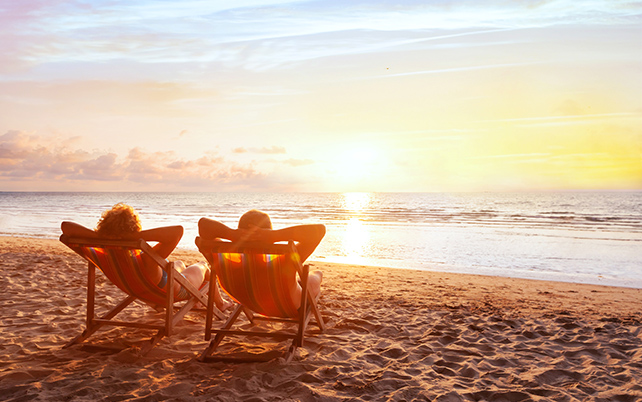 Retired couple relaxing on the beach watching the sunset